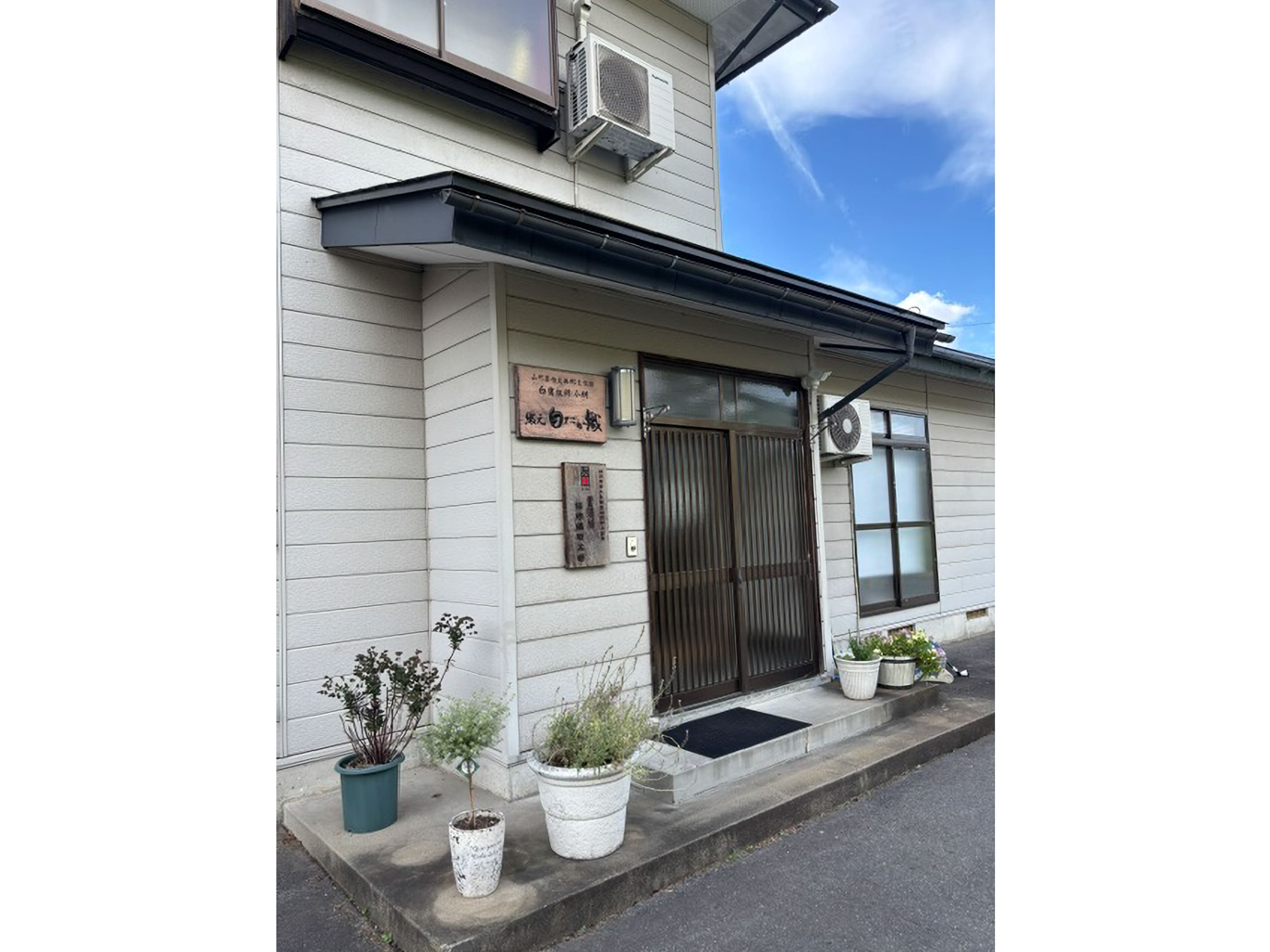 「山形県指定無形文化財」の看板が掲げられた、置賜紬を製作する織元「白たか織」の工房外観 