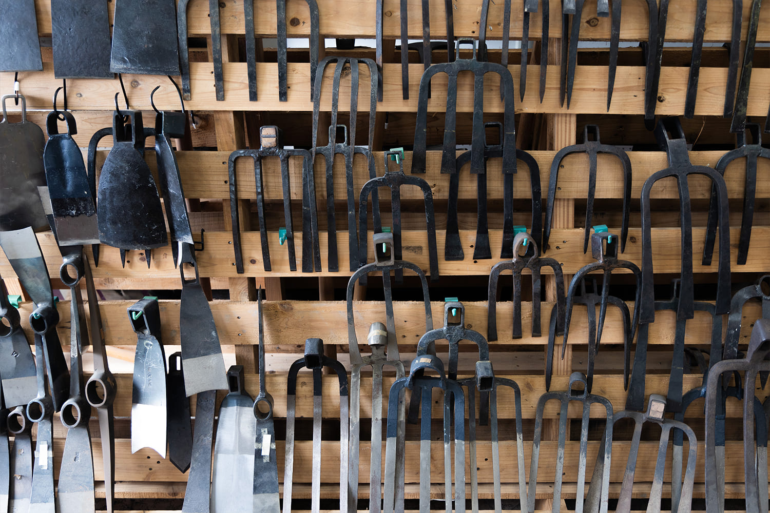 農具や工具が壁に整然と並ぶ鍛冶工房